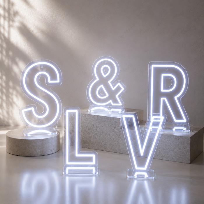 A 24" tall LED neon letter in cold white glowing brightly on a reception table supported by its sturdy acrylic base.