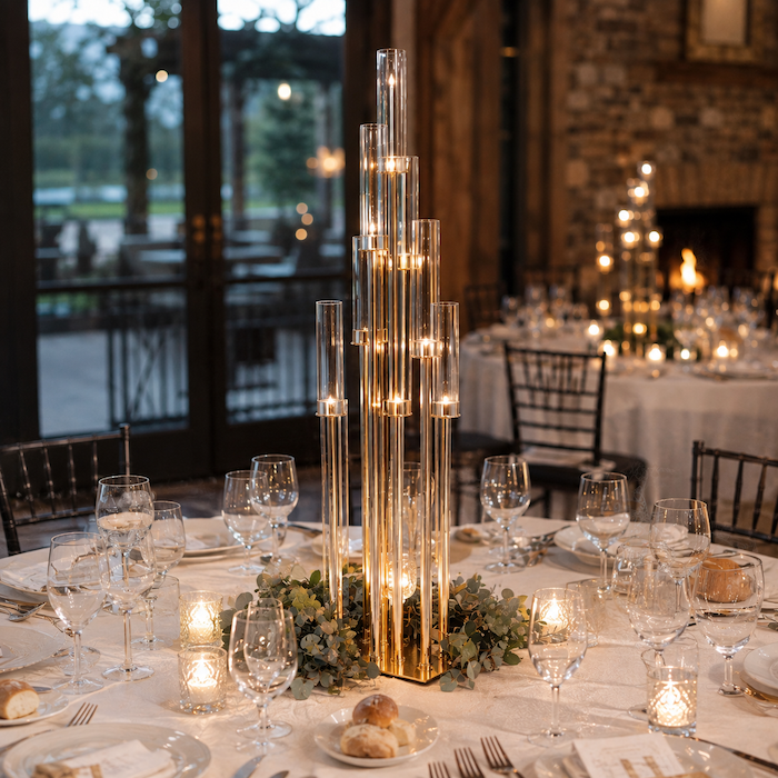 57.5-inch tall gold 10 arms cluster candle holder centerpiece with clear glass hurricane shades on a luxury wedding table.